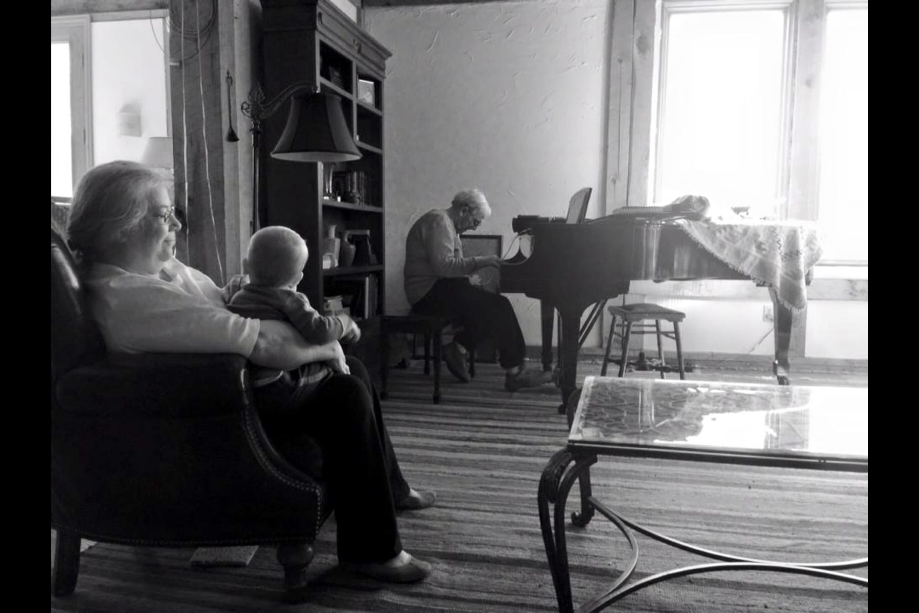 Ron playing piano and wife and grandchild listening